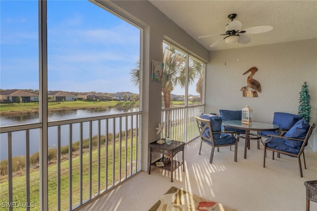 sunroom / solarium featuring ceiling fan and a water view