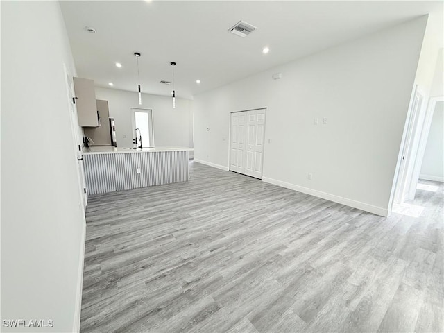 unfurnished living room with sink and light hardwood / wood-style floors