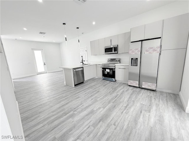 kitchen with gray cabinetry, decorative light fixtures, light wood-type flooring, kitchen peninsula, and stainless steel appliances