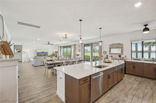 kitchen featuring visible vents, a sink, stainless steel dishwasher, open floor plan, and light countertops