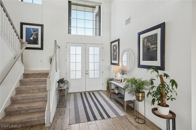 foyer entrance featuring visible vents, wood finished floors, stairway, french doors, and a high ceiling