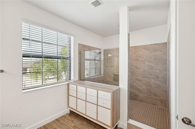 full bath featuring visible vents, a walk in shower, baseboards, and wood finished floors