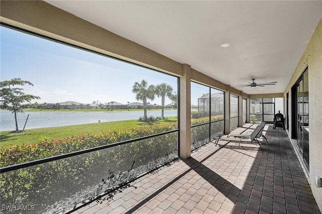 unfurnished sunroom featuring a ceiling fan and a water view