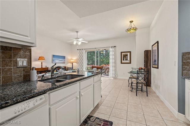 kitchen with white dishwasher, a sink, white cabinets, hanging light fixtures, and tasteful backsplash