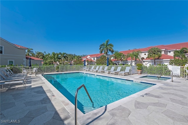 community pool with a patio, fence, a residential view, and a hot tub