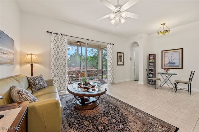 living room featuring a ceiling fan, arched walkways, baseboards, and light tile patterned floors