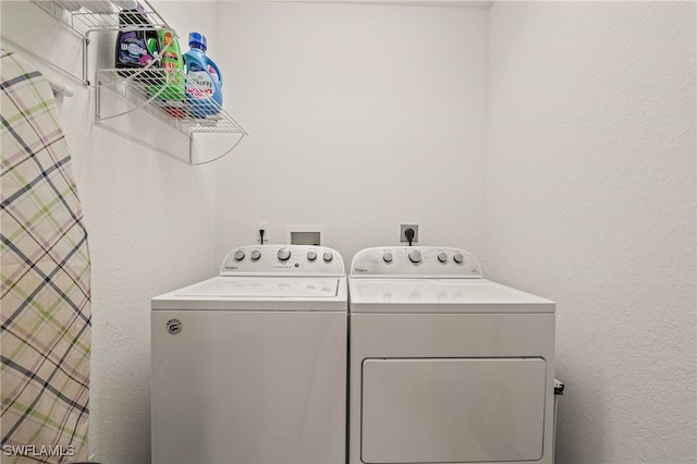 clothes washing area featuring laundry area, separate washer and dryer, and a textured wall