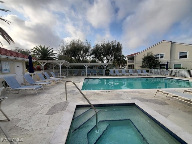 community pool featuring a patio area, a hot tub, and fence