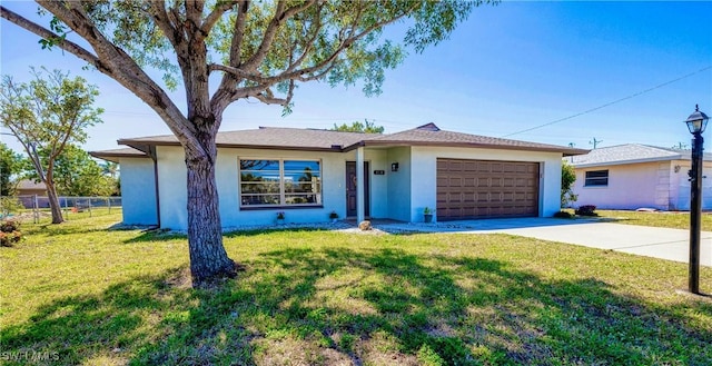 ranch-style home featuring a garage, concrete driveway, fence, and a front lawn