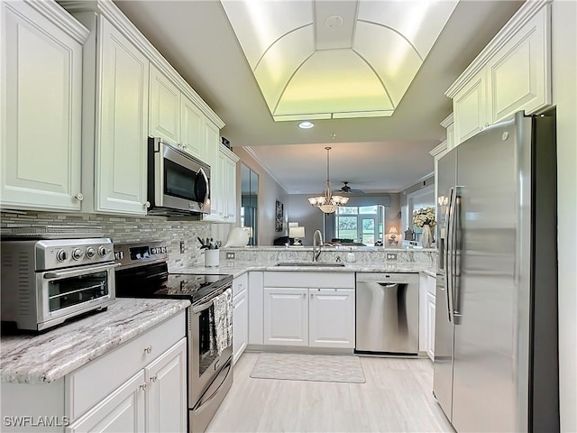 kitchen with sink, decorative light fixtures, appliances with stainless steel finishes, kitchen peninsula, and backsplash