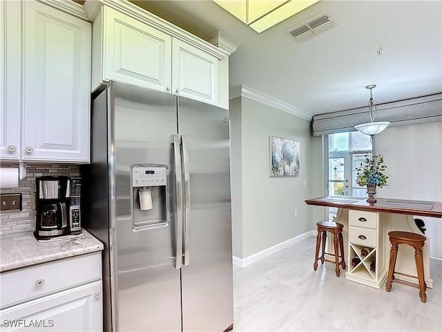 kitchen with crown molding, tasteful backsplash, hanging light fixtures, stainless steel fridge, and light hardwood / wood-style floors