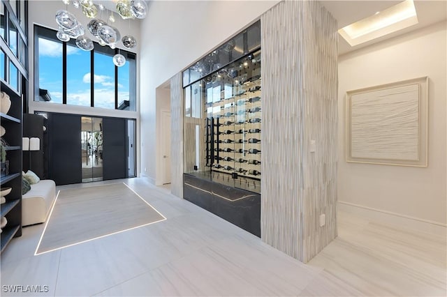 wine area featuring a towering ceiling and baseboards