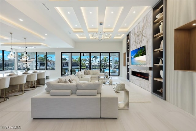 living area featuring an inviting chandelier, a premium fireplace, built in shelves, and recessed lighting