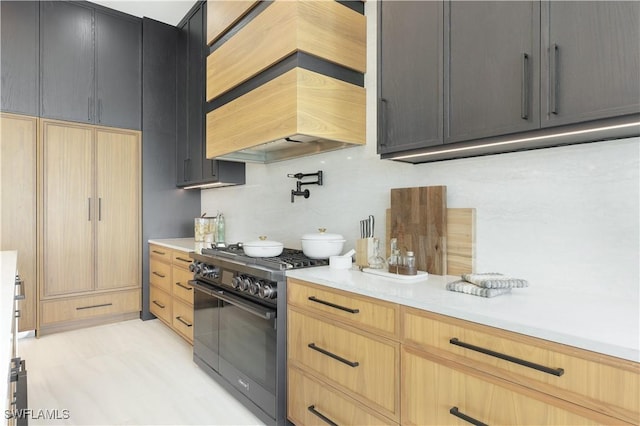 kitchen with double oven range, custom range hood, light brown cabinets, and light countertops