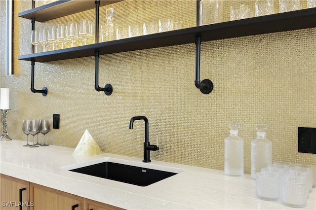 interior details with light countertops, brown cabinetry, a sink, and decorative backsplash