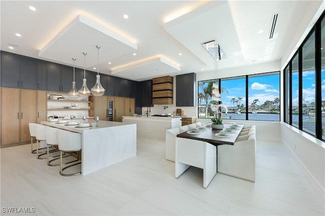 kitchen with a sink, light countertops, a large island, hanging light fixtures, and modern cabinets