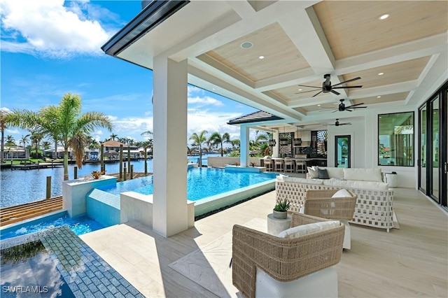 view of swimming pool with an infinity pool, outdoor dry bar, a water view, an outdoor hangout area, and a ceiling fan