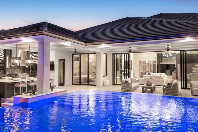 5346 Baypoint Ct, Cape Coral, FL 33904 - pool at dusk featuring an outdoor hangout area, an outdoor pool, ceiling fan, a bar, and a patio area