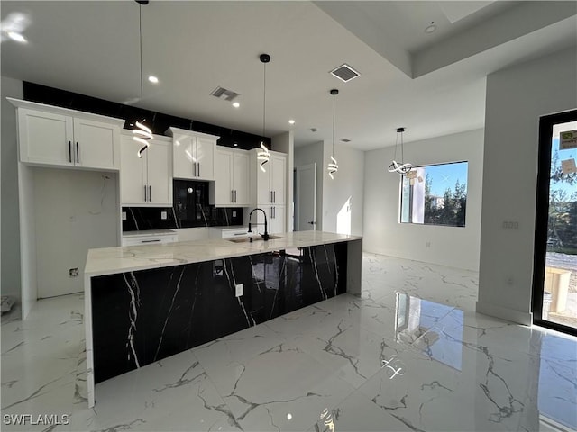 kitchen with marble finish floor, visible vents, white cabinets, and a sink