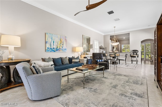 living area featuring ornamental molding, arched walkways, visible vents, and light tile patterned floors