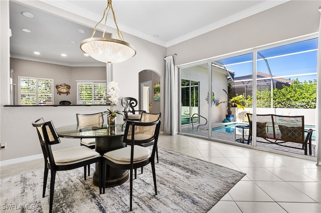 tiled dining area featuring arched walkways, recessed lighting, ornamental molding, a sunroom, and baseboards