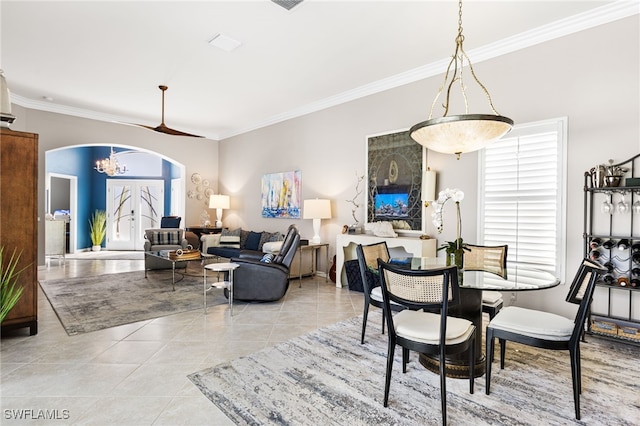 dining area with light tile patterned floors, arched walkways, a notable chandelier, and ornamental molding