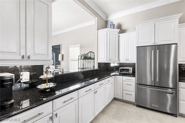 kitchen with freestanding refrigerator, white cabinetry, crown molding, and light tile patterned floors