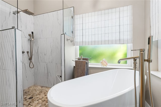 full bathroom featuring a freestanding tub, a marble finish shower, and a sink