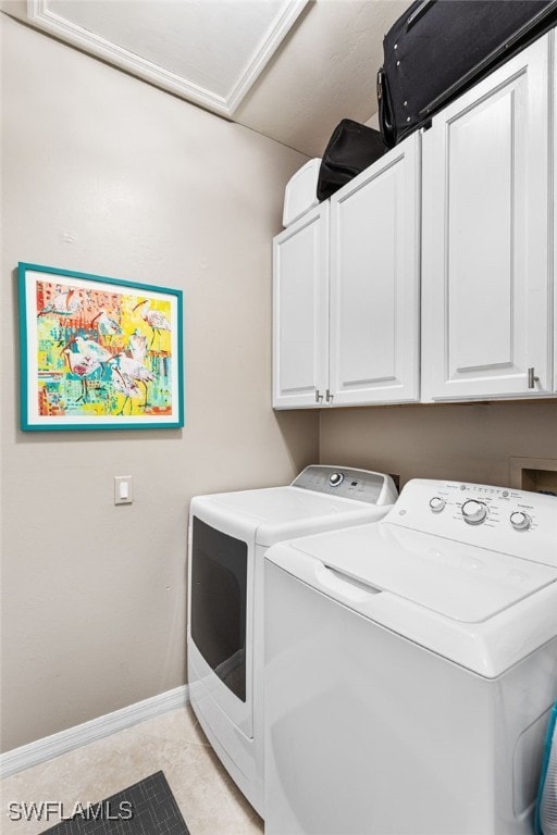 washroom featuring cabinet space, washer and clothes dryer, baseboards, and light tile patterned floors