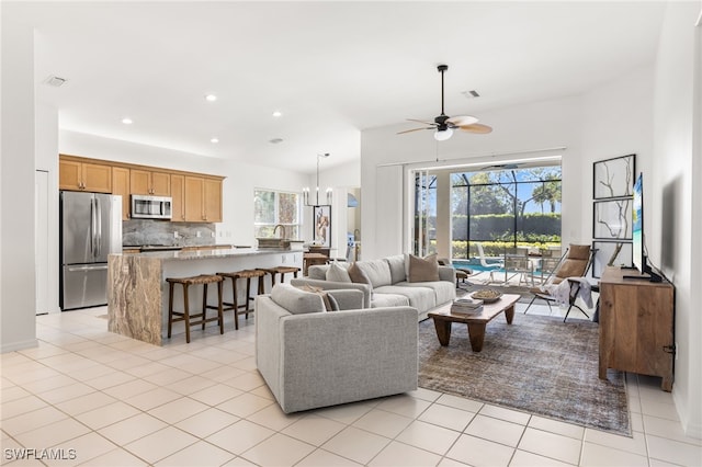 living area with light tile patterned floors, recessed lighting, visible vents, and ceiling fan with notable chandelier