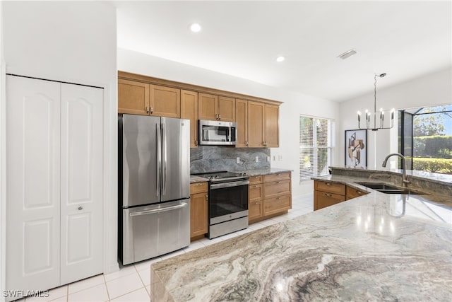 kitchen featuring visible vents, brown cabinetry, light stone countertops, stainless steel appliances, and a sink