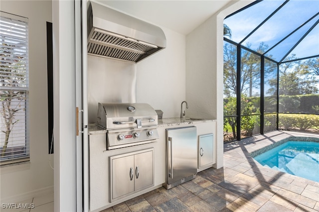 interior space featuring built in refrigerator, a sunroom, wall chimney exhaust hood, and a wealth of natural light