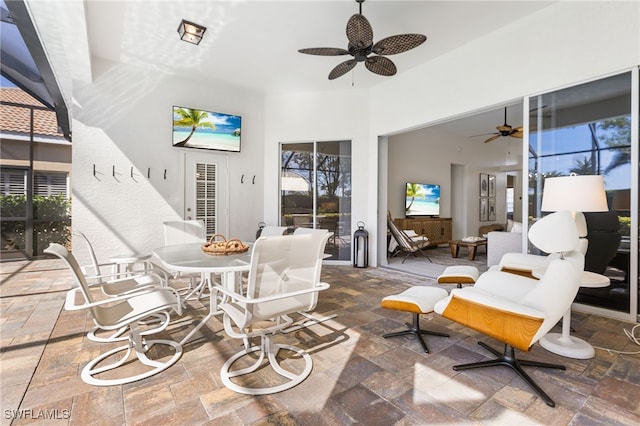 living area featuring a high ceiling, stone tile flooring, and a ceiling fan