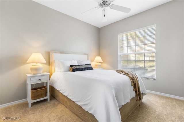 bedroom with a ceiling fan, light colored carpet, and baseboards