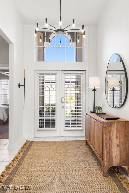 foyer entrance featuring a wealth of natural light, a notable chandelier, a high ceiling, and light tile patterned floors