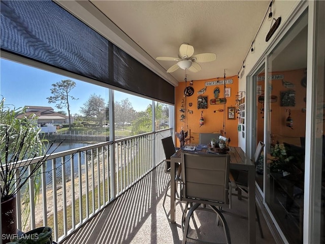 sunroom / solarium with a water view and ceiling fan