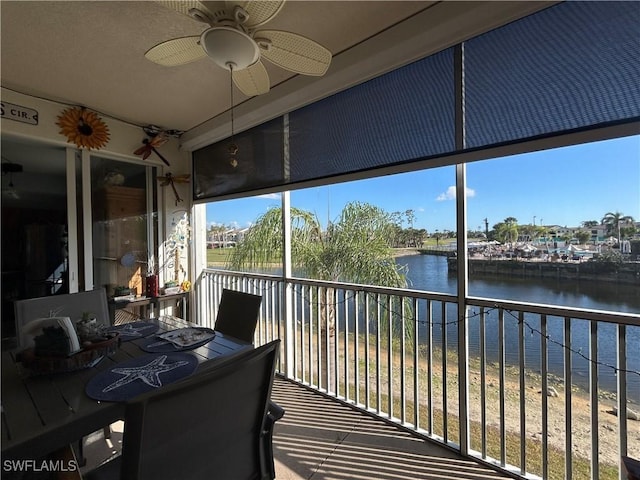 sunroom with ceiling fan and a water view