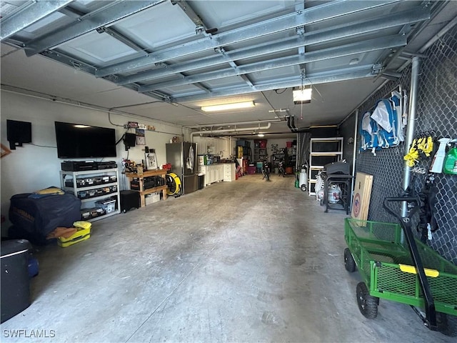 garage featuring a garage door opener, stainless steel fridge, and a workshop area