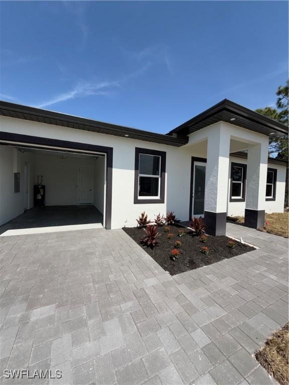 3310 14th St W, Lehigh Acres, FL 33971 - view of front of home with a garage, decorative driveway, and stucco siding