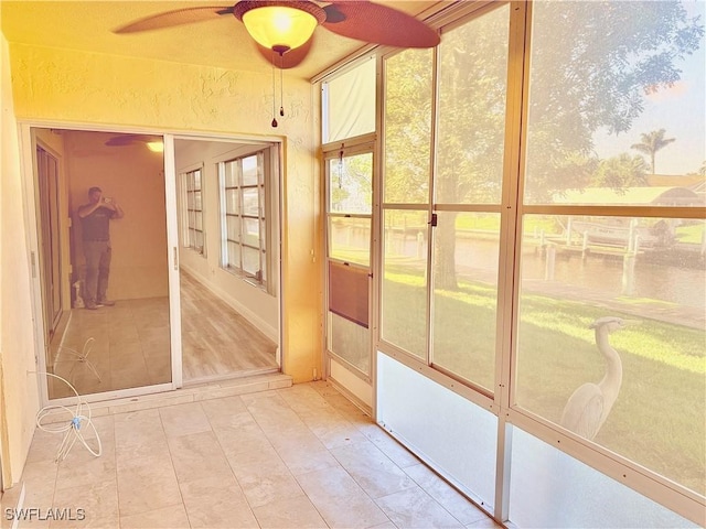 unfurnished sunroom with ceiling fan