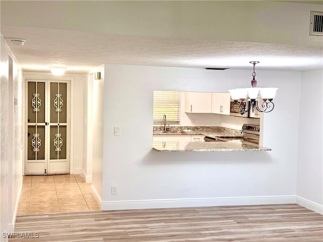 kitchen featuring appliances with stainless steel finishes, a textured ceiling, white cabinets, pendant lighting, and kitchen peninsula