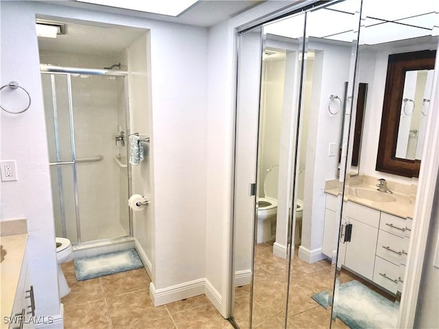 bathroom featuring a bidet, a shower with shower door, vanity, toilet, and tile patterned floors