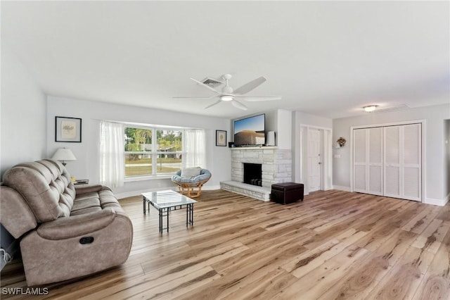 2084 Coral Point Dr, Cape Coral, FL 33990 - living room with light wood-type flooring, a ceiling fan, visible vents, a stone fireplace, and baseboards