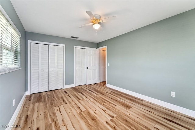 2084 Coral Point Dr, Cape Coral, FL 33990 - unfurnished bedroom with light wood-type flooring, a ceiling fan, visible vents, multiple closets, and baseboards