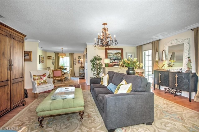 living room with a textured ceiling, ornamental molding, wood finished floors, and a chandelier