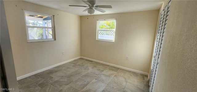 spare room with ceiling fan and baseboards