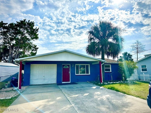 single story home with driveway, stucco siding, fence, and a front yard