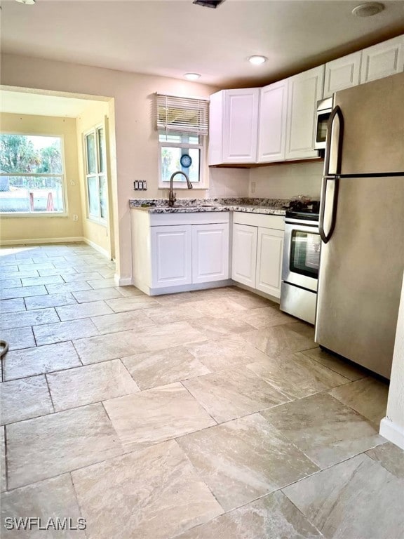 kitchen featuring white cabinets, a wealth of natural light, stainless steel appliances, and a sink