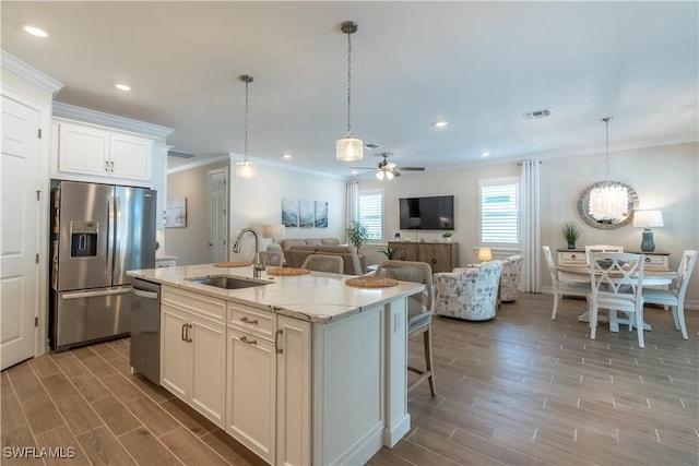 kitchen with sink, appliances with stainless steel finishes, white cabinets, an island with sink, and light stone countertops