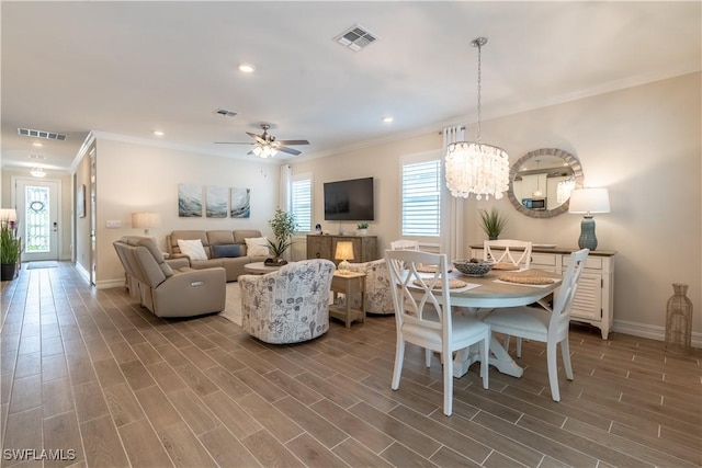 living room with ceiling fan with notable chandelier and crown molding